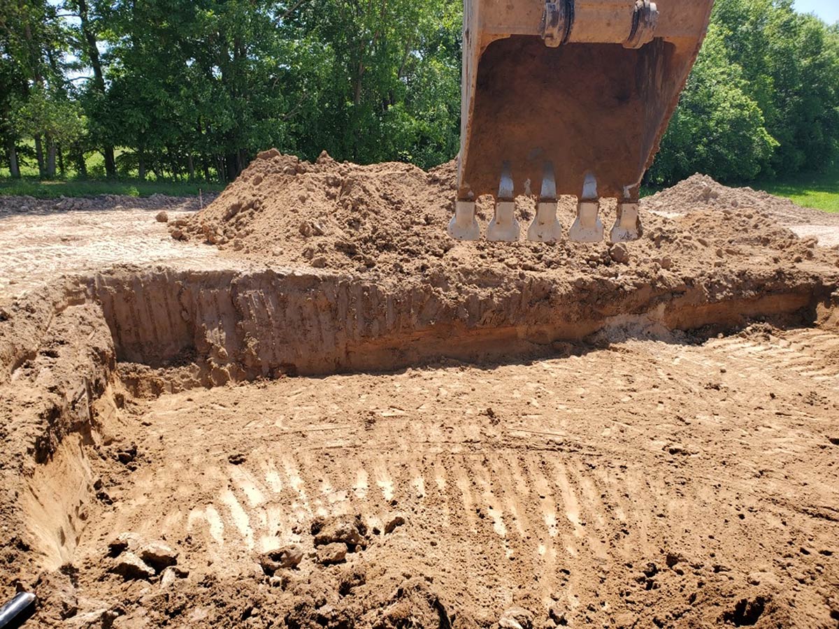 bucket of excavator over hole being dug