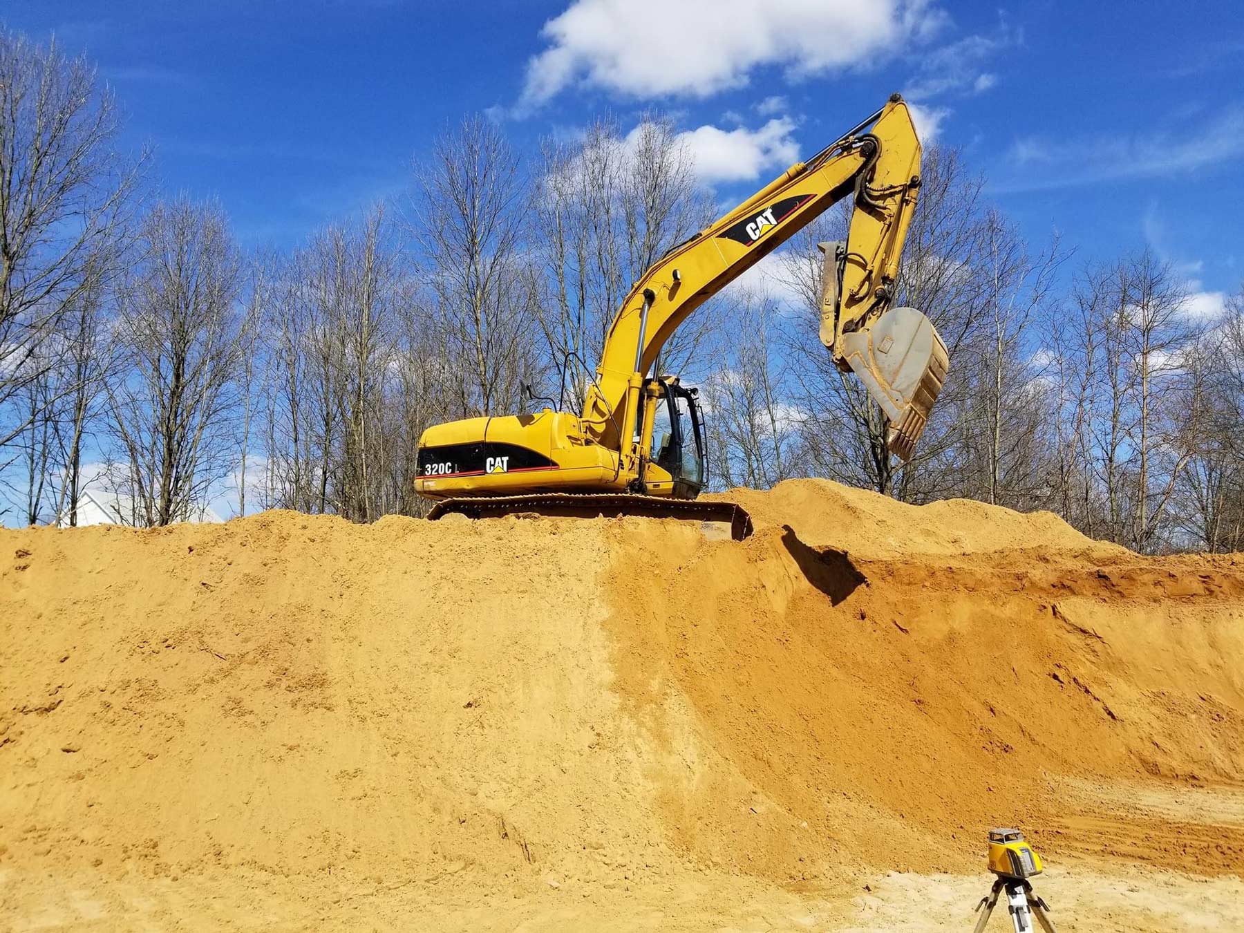 excavator on top of large sand pile