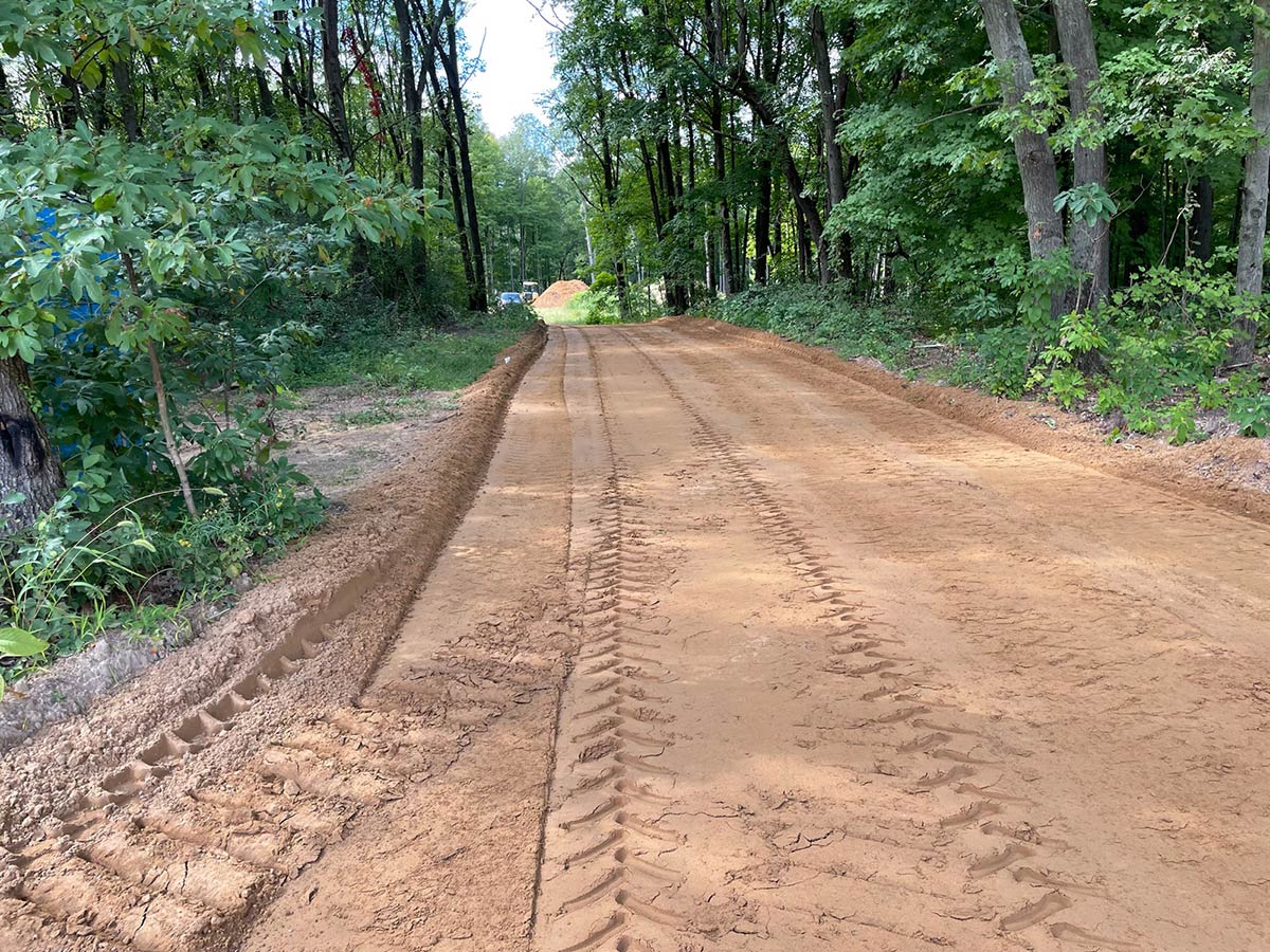newly excavated driveway through woods
